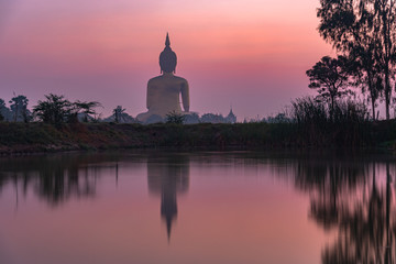 Fototapeta na wymiar reflection of the biggest Buddha in the swamp at sunrise..the great Buddha of Thailand is the largest Buddha statue in the world at wat Muang Ang Thong Thailand.