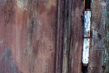 Old door hinges on a wooden door. Hinges rusty due to precipitation. The doors are very old