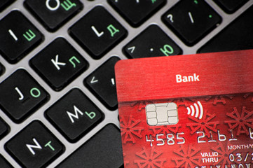 red bank card lies on laptop keyboard, concept of online payment and shopping