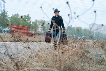 Obraz premium Hombre con sombrero negro, camisa y maletas