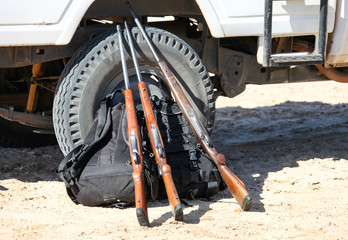 Three hunting rifles and backpacks at the wheel of the car.