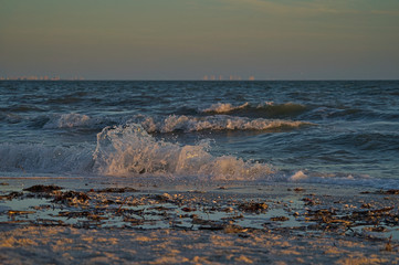 Gischt und schäumende Wellen am einsamen Naturstrand während des Sonnenuntergangs