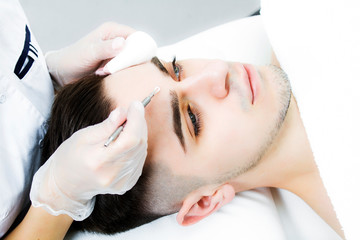 Naklejka premium Manual face cleansing at the beautician. A man on the procedure for treating facial skin from acne.