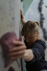 Female athletic climber, woman is climbing, bouldering at an indoor boulder rock hall