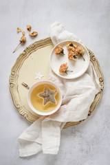 A cup of tea on a vintage tray and some dried roses in plate