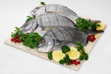 Sarago con prezzemolo, insalata e limone su piano di marmo