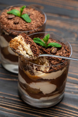 Classic tiramisu dessert in a glass cup on wooden background