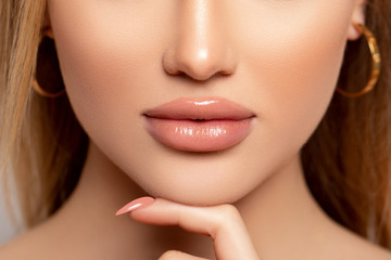 Fototapeta premium Sexy Lips. Make up. Close up Beautiful photo Lips. Manicure. Beauty Fashion Woman Lips with natural Makeup. shine Lipstick. Isolated. Macro Mouth Caramel Colors lacquered model touches her lips 