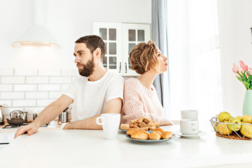 Distant Couple Sitting At The bright kitchen at home And Not Talking