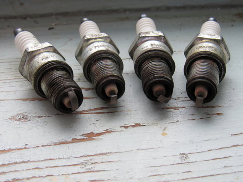 four used car spark plugs on the wood