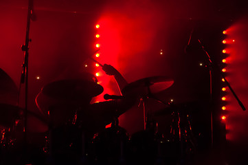 silhouette of a drummer on stage under red lighting