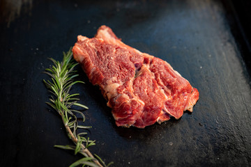 On black stove, roasting piece meat, sprig rosemary