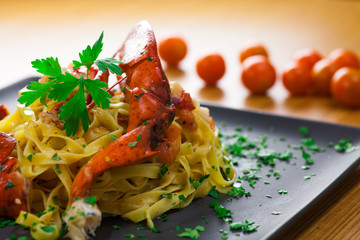 Plato de pasta picante de bogavante sobre tabla con ingredientes frescos