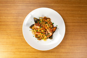 Plato de pasta italiana de marisco con mejillones y gambas sobre tabla de madera