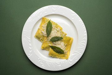 Ravioli al brasato con burro salvia e Grana Padano, su fondo verde