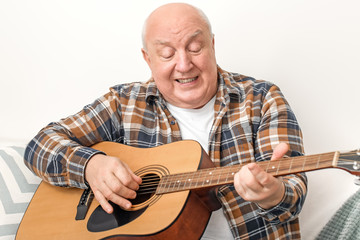 Portrait of elderly man playing guitar at home