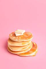 Tasty pancakes with honey and butter on color background
