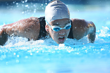 nadadora competindo de touca e óculos na piscina