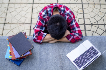Boy student tired from studying sit and rest on the school desk.