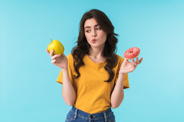 Woman posing isolated holding apple and donut.