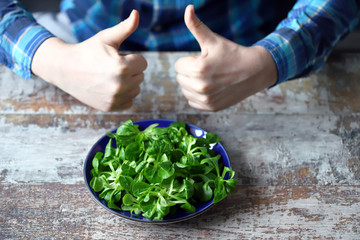 Selective focus. Men's hands hold a green salad. Male hand shows ok sign. Diet concept. Healthy food concept. Mash salad in a blue plate.