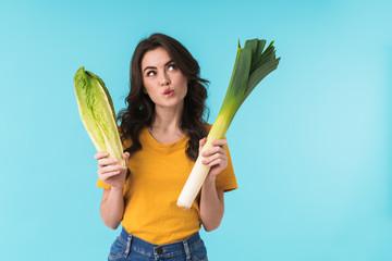 Thinking young beautiful woman holding cabbage and leek