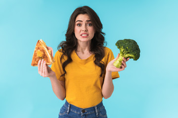 Confused beautiful woman holding sandwich and broccoli.