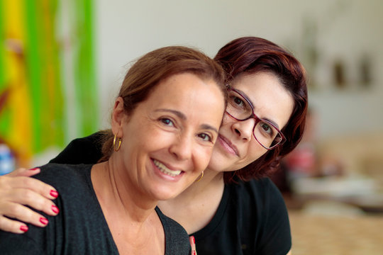 Amigas abra&ccedil;adas e sorrindo na cozinha