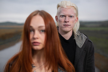 Young albino man and redhead girl stand on a country road - obrazy, fototapety, plakaty