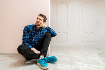 a young handsome person sit on the floor and thinking and relax, lean on the wall