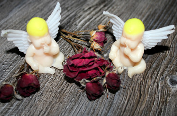 Handmade soap in the shape of angels on a wooden background with dried roses
