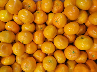 A lot of juicy tangerines stacked in a big pile, background texture