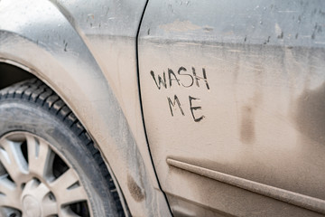 wash me text handwritten on the car vehicle during bad rainy weather season