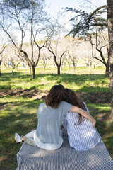 dos chicas disfrutando de una tarde primaveral en un parque lleno de almendros en flor