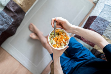 top view of a person's hands hold a white plate with a fruit salad mix, morning breakfast