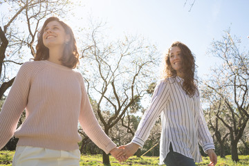 two young girls enjoying a spring day in an outdoor park surrounded by flowering trees