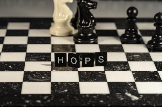 The concept of Hops represented by black and white letter tiles on a marble chessboard with chess pieces