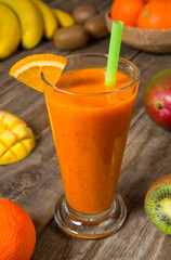 Mango orange banana and kiwi smoothie with ingredients on a wooden table. Selected focus.