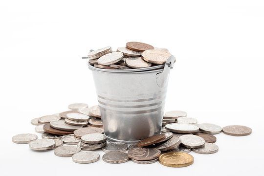 Invest money, smart finances and cash profits concept with metal coin bucket with some coins spilling around isolated on white background and clipping path cutout