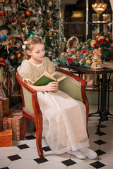 smart girl at home sitting with a book near the New Year tree