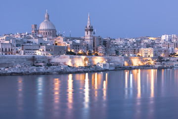 Fototapeta na wymiar Mystical Valletta with Our Lady of Mount Carmel church and St. Paul's Anglican Pro-Cathedral at sunset as seen from Sliema, Valletta, Malta