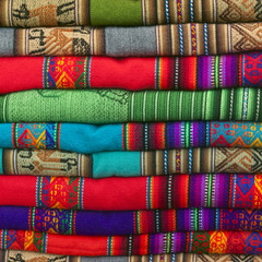 A pile of colorful Andean textiles photographed in the local handicraft market of Cusco