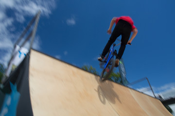  Bmx rider jumping over on a U ramp in a skatepark (motion blurred image)