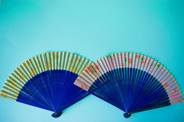 Composition of navy blue female hand fans close-up on the light blue paper background.