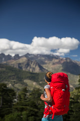 Fototapeta na wymiar Pretty, female hiker in high mountains packing her backpack