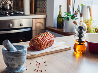 Uncooked spicy pork meat roulade prepared to roast, marinated with spices and herbs on a wooden plate. Meatloaf on table prepared to roast, marinated with spices and herbs. Olive oil in glass bottle.