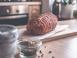 Uncooked spicy pork meat roulade prepared to roast, marinated with spices and herbs on a wooden plate. 