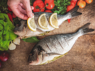 Raw dorado fish with spices and lemon cooking on cutting board. Top view