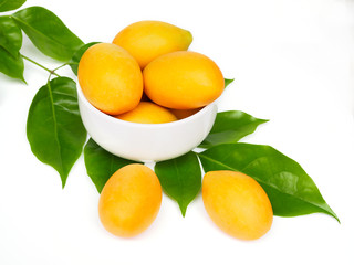 Sweet yellow marian plum fruit, maprang or mayongchid in bowl with green leaves isolated on white background. - obrazy, fototapety, plakaty