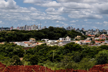 Sky line  de  cidade no horizonte. Cidade rodeada por bosques verdes. Dia ensolarado.